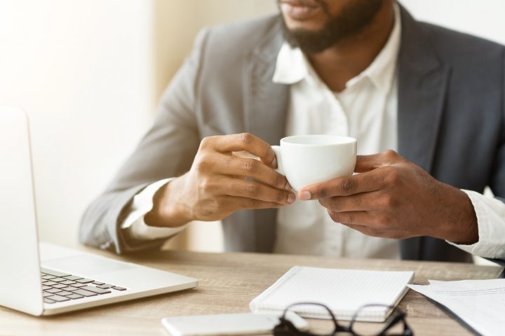 Pensive businessman drinking coffee at workplace, thinking about new project