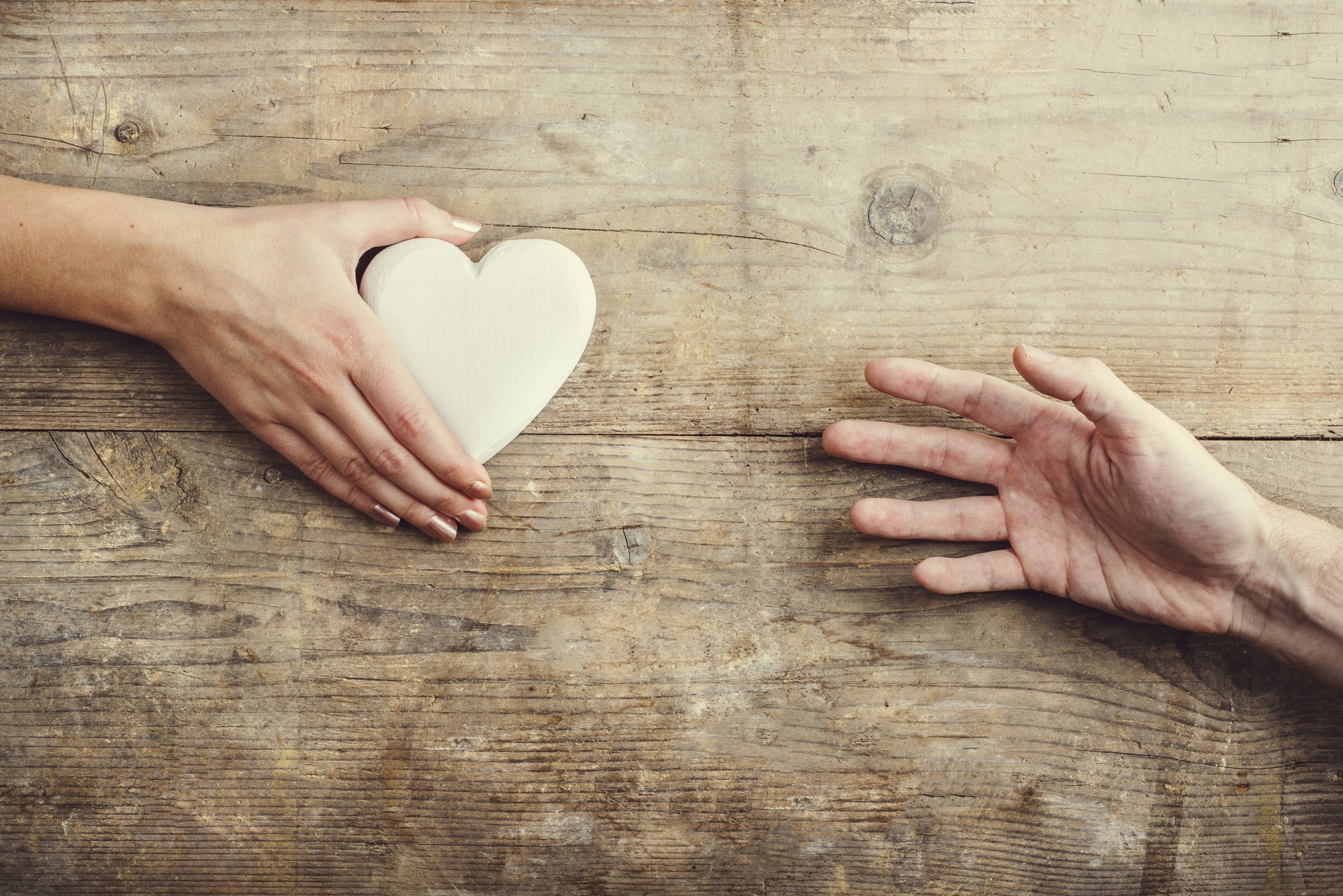 Man reaching for a heart to woman.